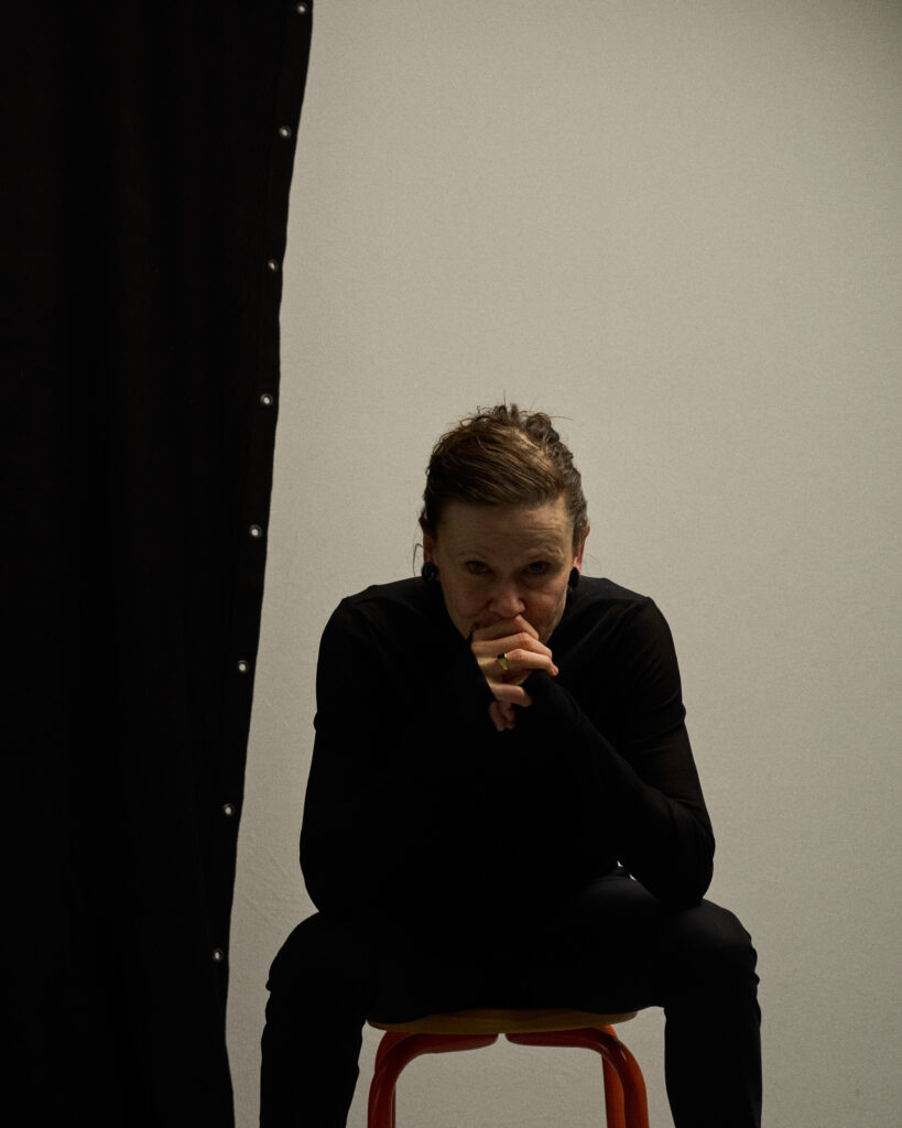 Portrait von Regula Imboden im Studio sitzend mit einem nachdenklichem Blick.